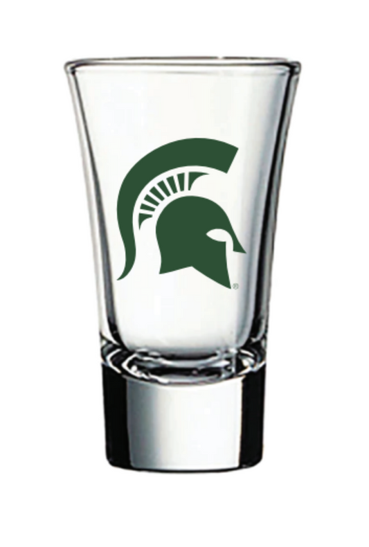A clear heavy bottom shot glass with a flared top and a green screen print of a Spartan Helmet logo.